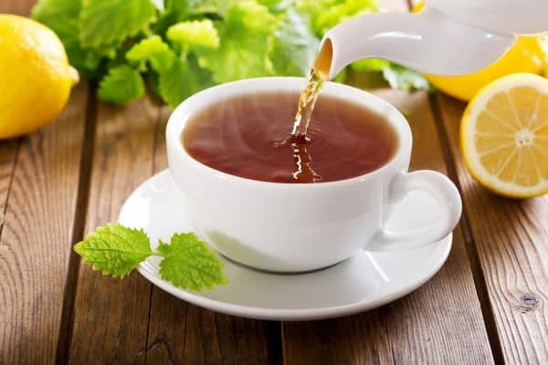 Forfriskende og lækker kop te i omgivelser med flotte citroner og urter